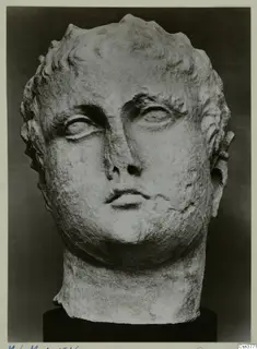 Marble head of a youth with curly hair, photographed against a dark background on a black base.