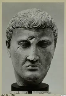 Roman stone head of a man with short, wavy hair, shown on a dark cylindrical base