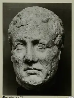 Roman stone head of a man with short curled hair, photographed against a dark background