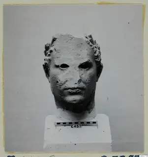 Roman sculpture: stone head on a white plinth, front view, with a scale bar and number label