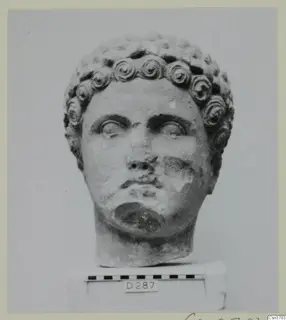 Roman sculpture: carved stone head with curled hair, shown on a base beside a scale bar.