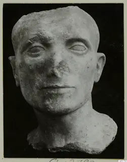 Roman sculpture: a stone head of a man with cropped hair, its nose chipped, with a broken bust below.
