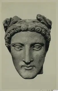 Head of a youth in stone, with curled hair and a leafy headband, face turned towards the viewer