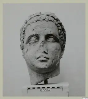 Stone head with short curled hair, shown on a plinth beside a scale bar
