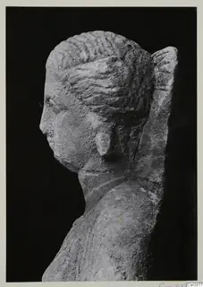 Stone sculpture of a head and upper body in left profile, set against a black background
