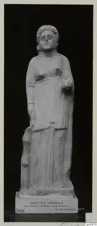 Standing stone statue of a draped female figure, shown front-on against a dark background
