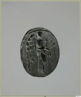 Oval seal or gem engraved with a standing figure in a long garment, photographed on a grey card