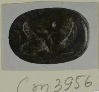 Oval engraved gem in dark stone, with pale engraved lines, shown on a grey card