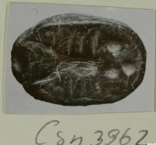 Oval engraved seal or gem in dark brown stone, photographed on a grey card