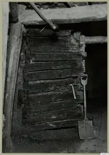 Square timber crib lining of an ancient vertical shaft in a copper mine, with a shovel and hammer beside it