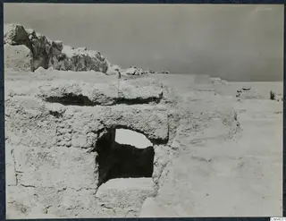 Excavated stone walls and blocks at Vouni palace, with a rectangular opening in a wall and open ground beyond