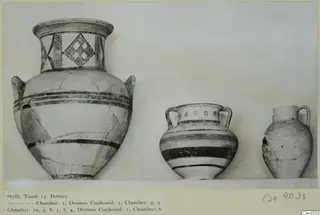 Three painted pottery vessels from Stylli Tomb 13 standing in a row on a shelf.