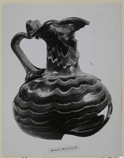 Blown glass jug with wavy light threads and a looped handle, shown with a scale bar.