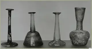 Four blown glass vases standing in a row, each with a narrow neck and flared rim