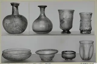 Eight glass vessels, bottles, beakers and bowls, shown in two rows against a pale background