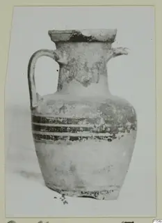 Pottery jug with a strap handle, a small spout and dark bands around the upper body