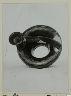 Black glazed ring-shaped vessel with a short spout and a pale leaf pattern, shown against a light background