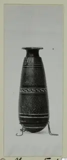 Tall narrow vessel with a flared rim, banded painted decoration, a meander band and lattice pattern, standing on a wire stand