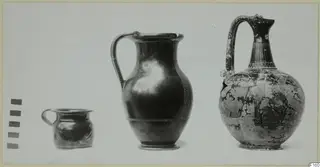 Three pottery vessels of different sizes standing in a row against a pale backdrop, from small at left to large at right.