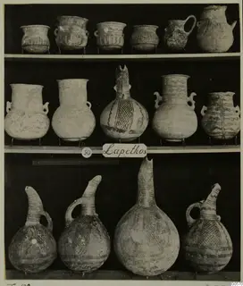 Pottery vessels from Lapithos Markides Tomb 50 arranged on three shelves against a dark background.