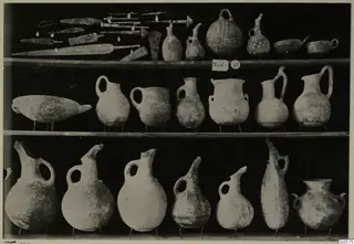 Lapithos Markides, T.49: metal blades and jugs on three shelves against a black background