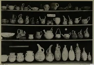 Rows of pottery jugs, juglets and bowls displayed on shelves, from Lapithos T.21