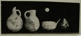 Four pottery vessels from Lapithos Markides, tomb 52: two jugs, a spouted bowl and a small jar, on a dark background.