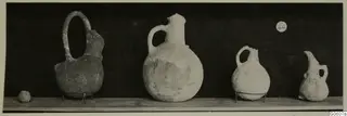 Four jugs from Lapithos Markides T.44 on a wooden shelf against a dark background.