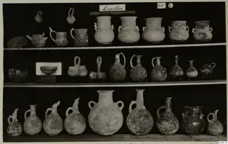 Pottery jugs, juglets and bowls from Lapithos Markides, T.4, displayed on three shelves.
