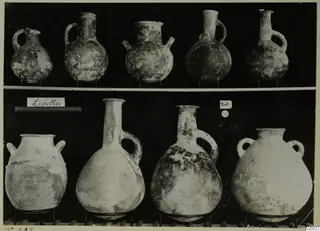 Pottery jugs and jars from Lapithos Markides, T.203, in two rows on wire stands.