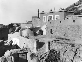 Village buildings and people at Mandres, with plastered walls, flat roofs and a domed structure in the foreground