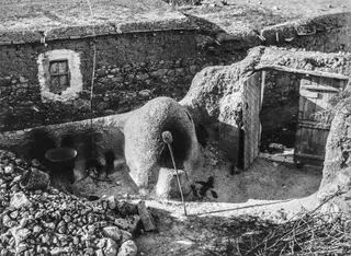 Domed clay bread oven in a sunken yard at Mándres, beside a stone wall and an open wooden door