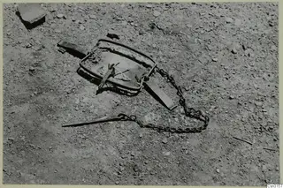 Animal trap, called pagida in Greek, with a chain, lying on stony ground.