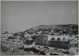 Village of flat-roofed stone houses on a rocky hillside on the Karpas peninsula, with one man walking on a path