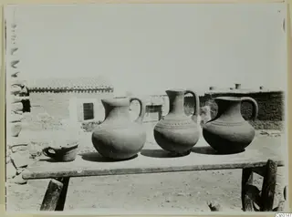 Three modern water jars and a small cup on a wooden table at farmstead A, Klirou