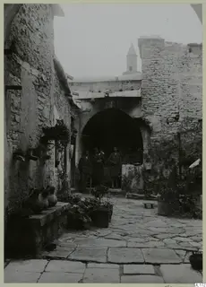 Stone-paved courtyard at Kalavasos with large jars on a ledge and people standing in an archway