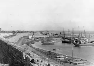 Harbour at Famagusta with moored sailing vessels and small boats beside a long city wall.