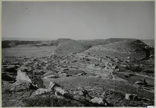 Village of low buildings spread across a valley at Galinoporni, Karpas peninsula, seen from rocky high ground.