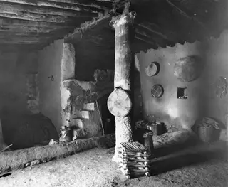 Interior of a traditional house with a timber pillar, mud-plastered walls and a stepped mud structure