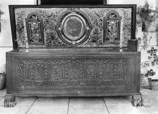 Cypriot clothes chest with carved front panel and painted lid, photographed on a paved courtyard