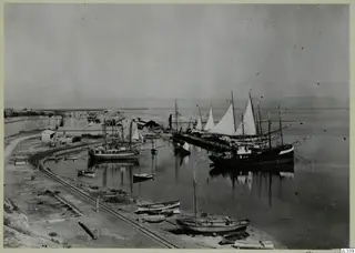 Harbour at Famagusta with moored sailing boats and rowing boats beside a railway track and city wall