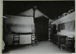 Interior of a room at Lazania with a canopied bed, wooden chairs, a dark cupboard and a chest