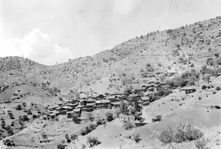 Village of Lazania built on a steep, terraced hillside, with houses and trees below the slope