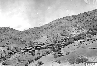 Village of Lazania built on a steep dry hillside, with houses clustered among scattered trees and bare slopes