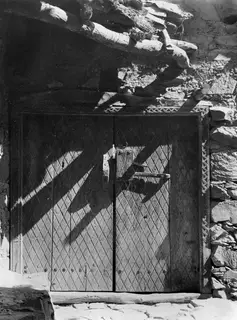 Wooden double door with a diagonal lattice pattern and iron fittings, set in a stone wall at Lazania