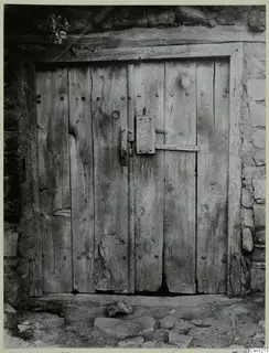Old wooden double door with iron studs and a carved lock plate, set in a stone wall at Lazania