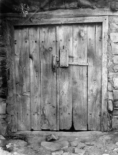 Wooden plank door with iron latch and studs set in a stone wall at Lazania