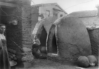 Two domed clay pottery kilns at Klirou, farmstead A, with a man in the middle holding a large jar