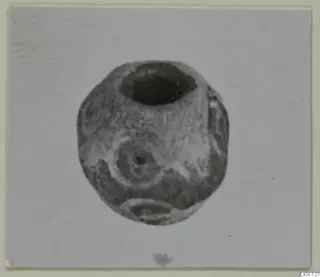 Rounded stone object with a wide opening at the top and a ring-shaped motif on its face