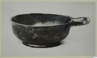 Black-glazed bowl with a single horizontal handle, shown in side view against a pale background.
